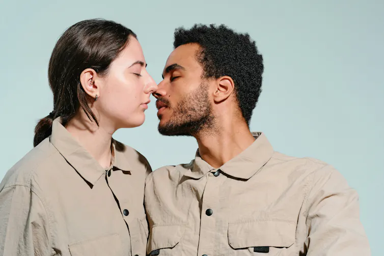 Une femme aux cheveux longs et un homme aux cheveux courts et à la barbe sur le point de s’embrasser