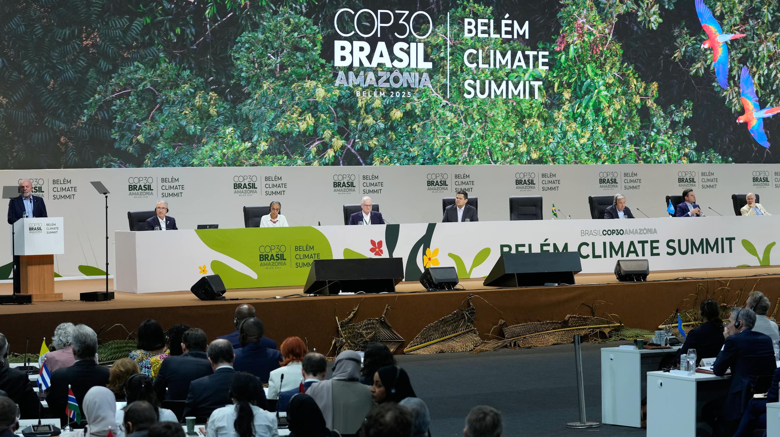 people attend a convention in a large hall. COP30 Brasil is written in large letters on the wall behind a dais