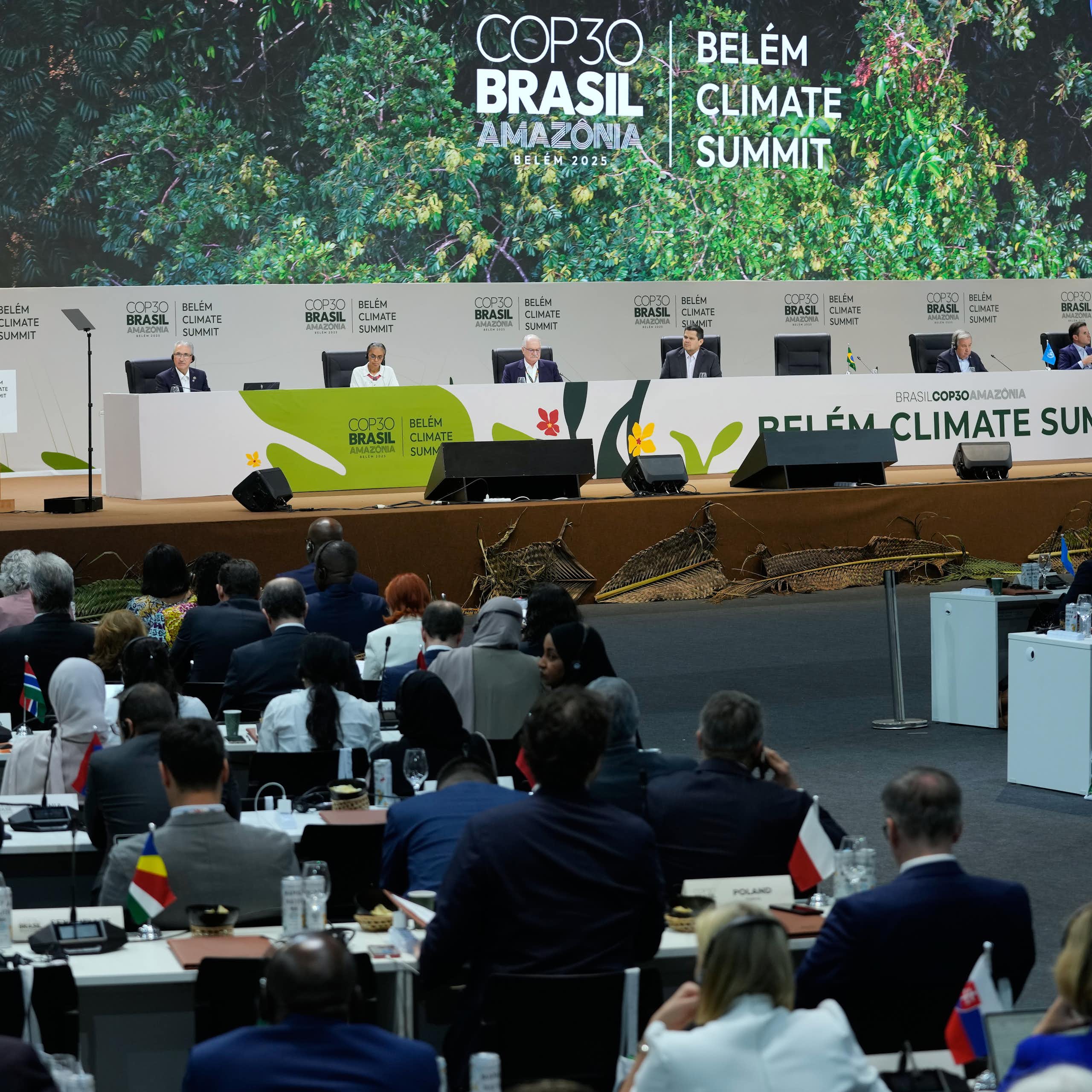 people attend a convention in a large hall. COP30 Brasil is written in large letters on the wall behind a dais