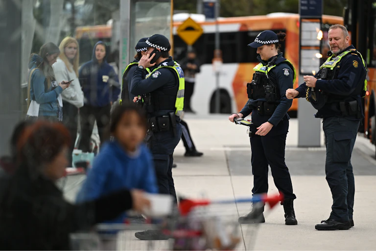 Several police officers chat with young people on a street.