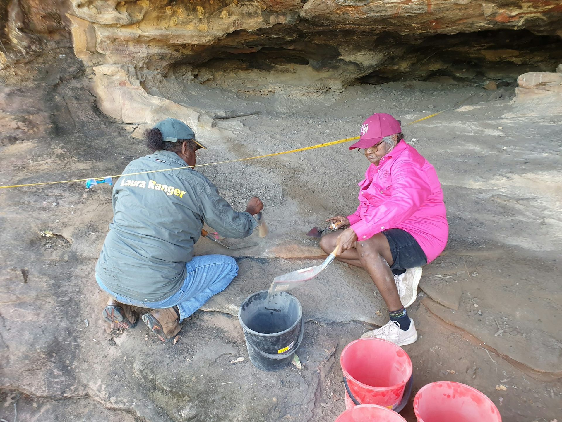 Two women excavating in a rock shelter site.