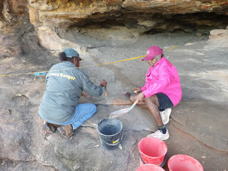 Two women excavating in a rock shelter site.