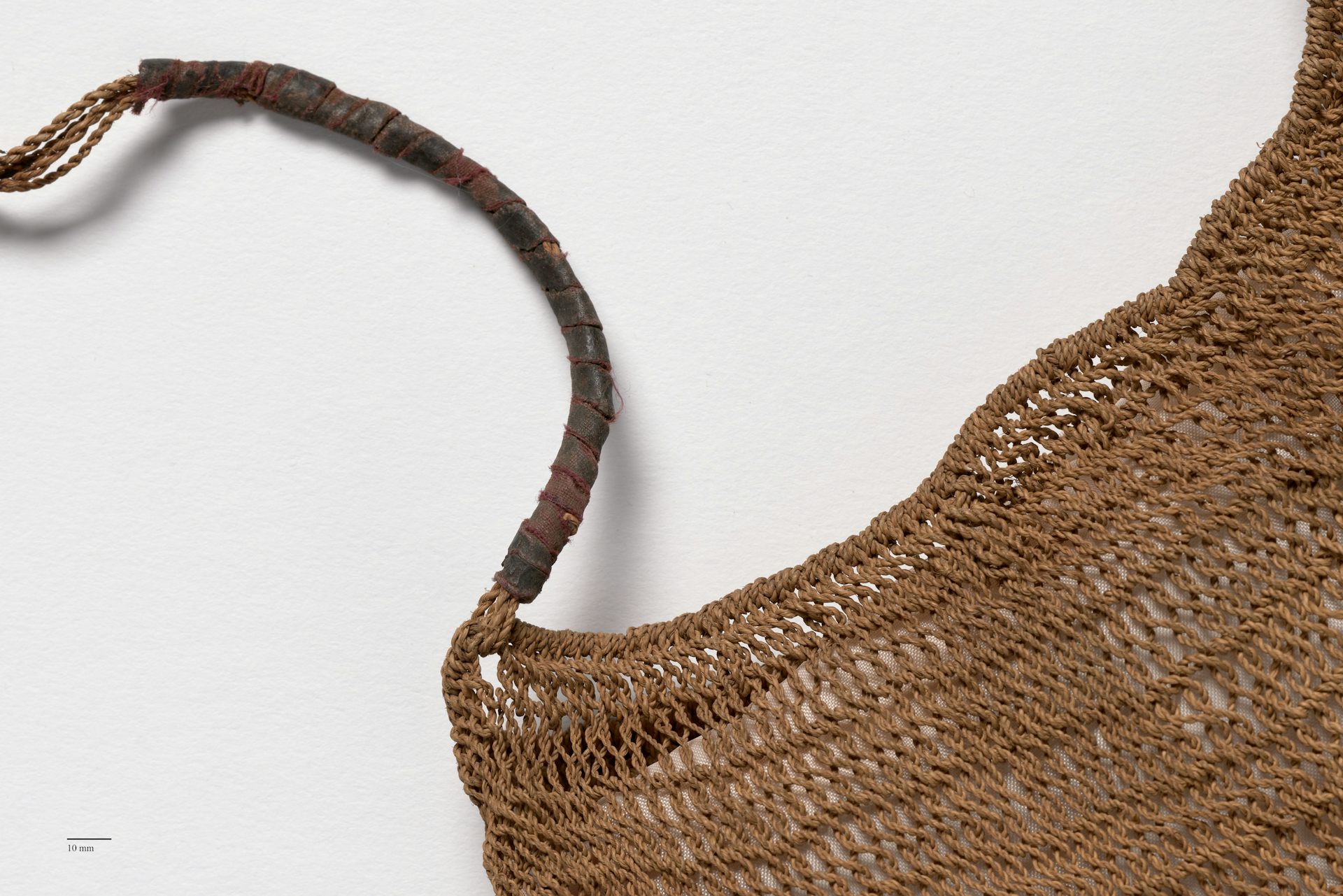 Partial view of a woven string bag and its handle.