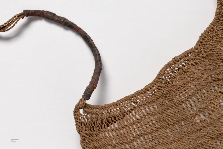 Partial view of a woven string bag and its handle.