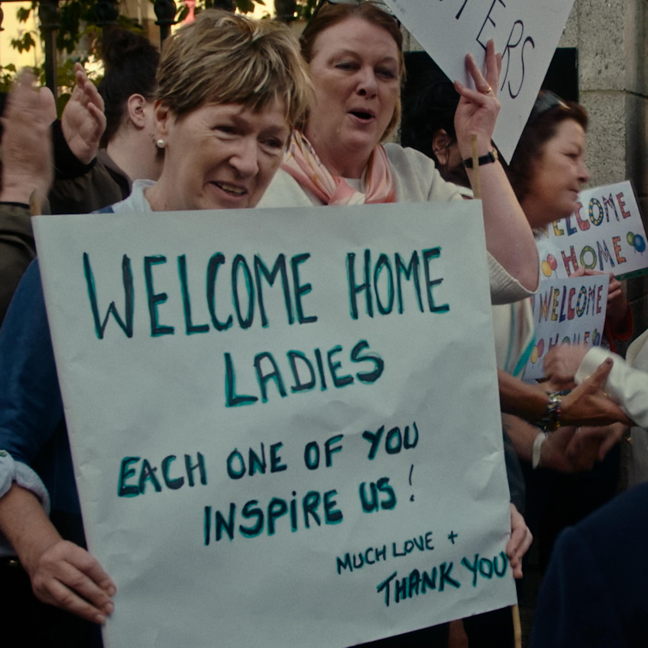 People holding up welcome signs
