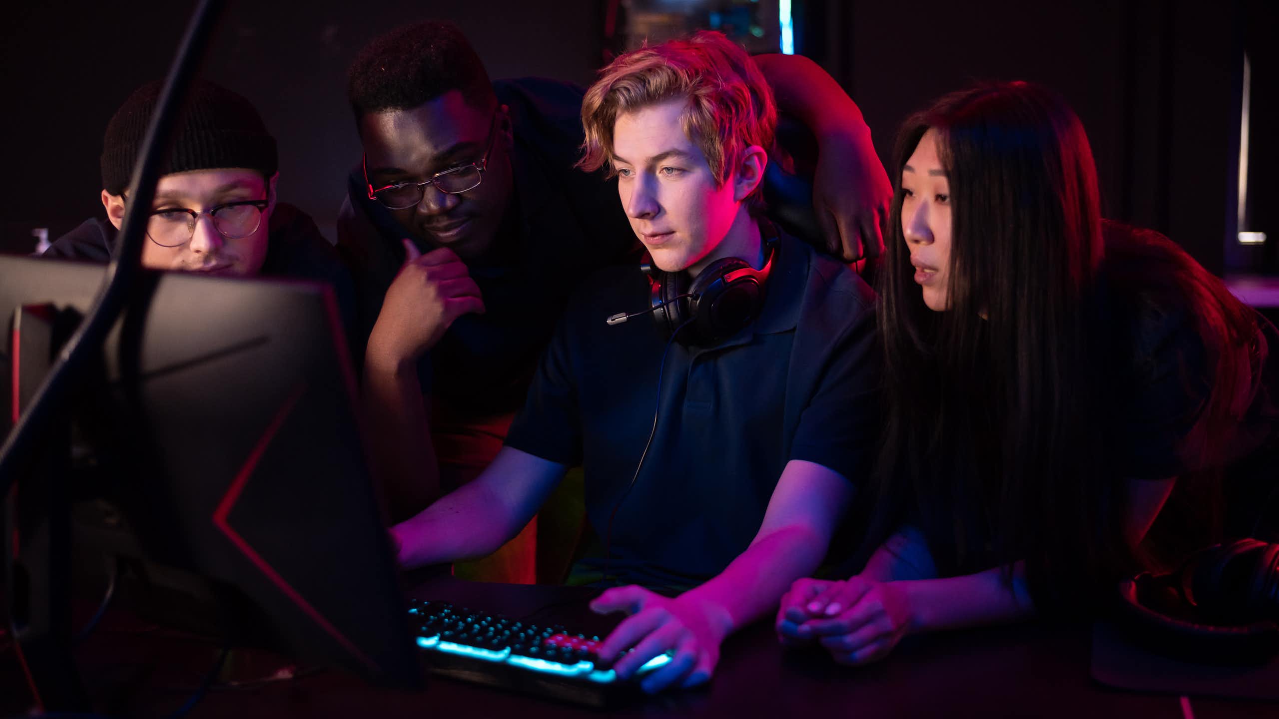 Des jeunes gens, hommes et femmes, en train de jouer devant un écran d'ordinateur.