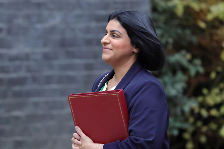 Photo of Shabana Mahmood in profile, walking with a red minister's folder