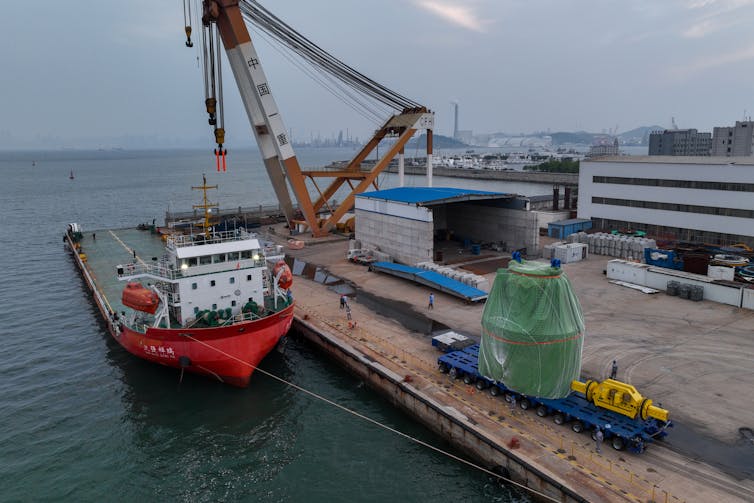 What are small modular reactors, a brand new form of nuclear energy plant sought to feed AI’s power call for? 1 A large green item is on a pier next to a ship and a crane.