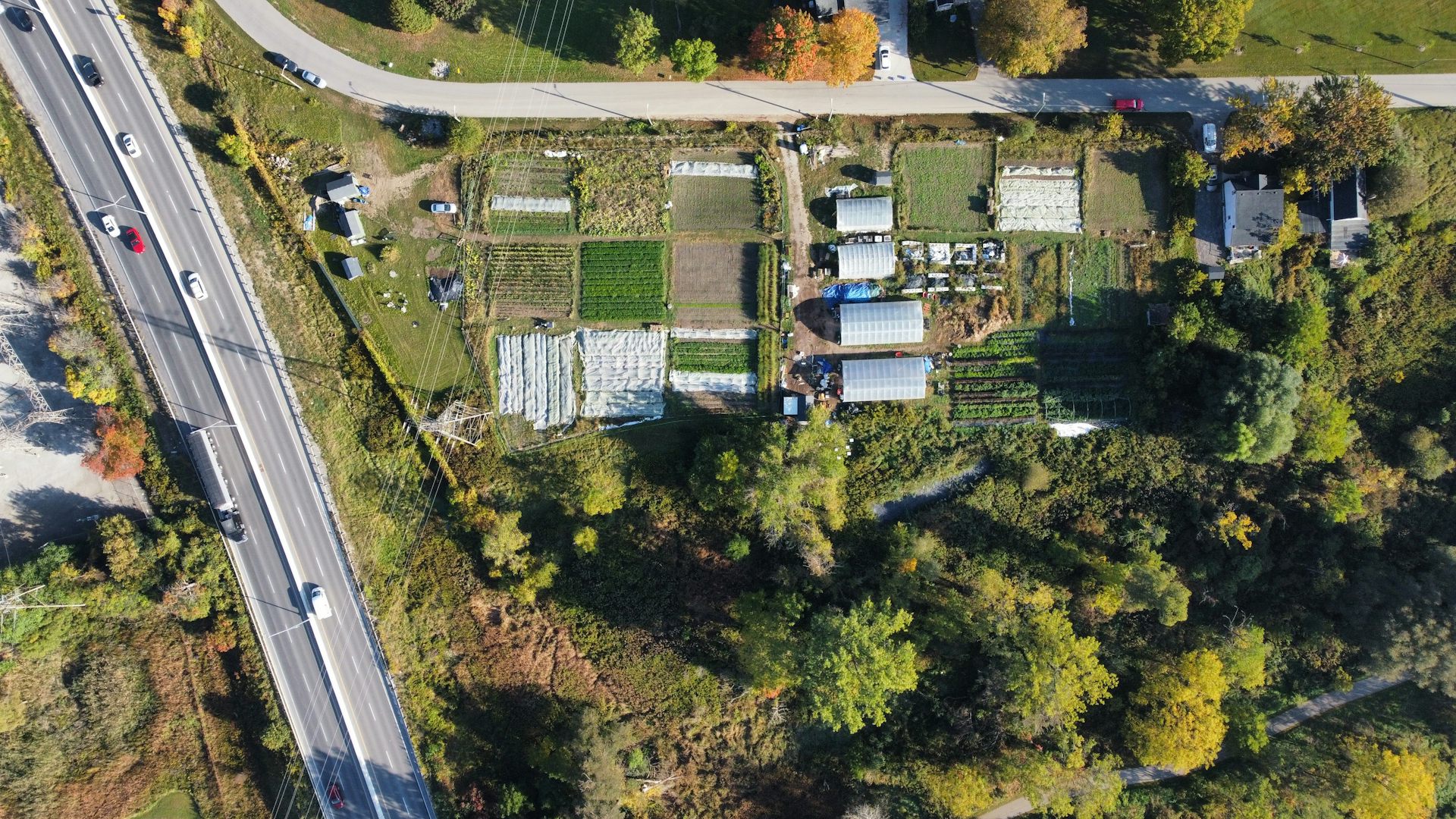 an aerial photo of a small farming area with greenhouses next to a highway