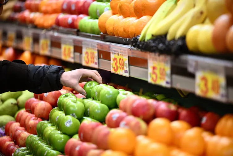 Shopper picking up an apple from a fruit stall