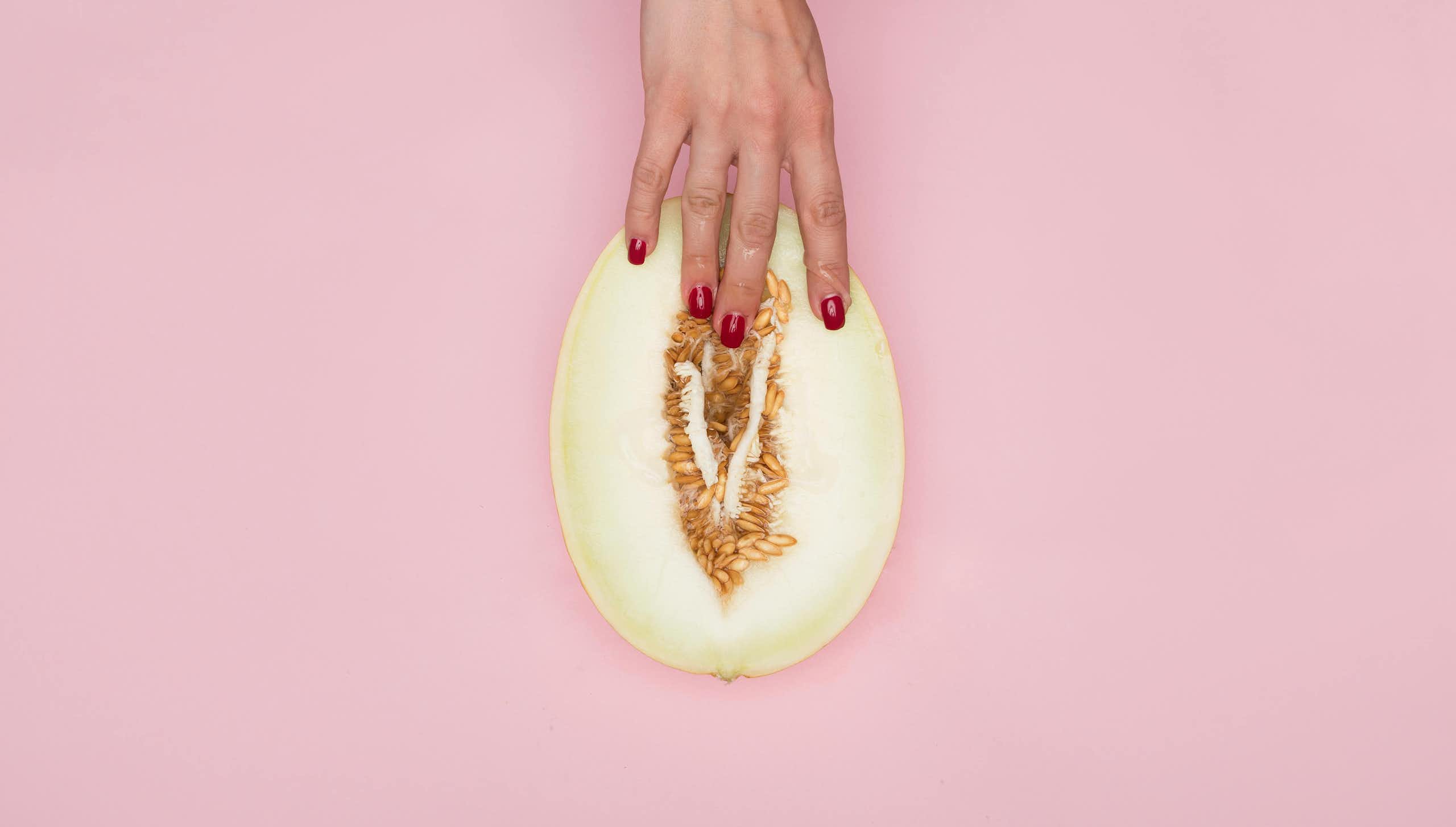 Woman's hand holding melon, fingers inserting fleshy part