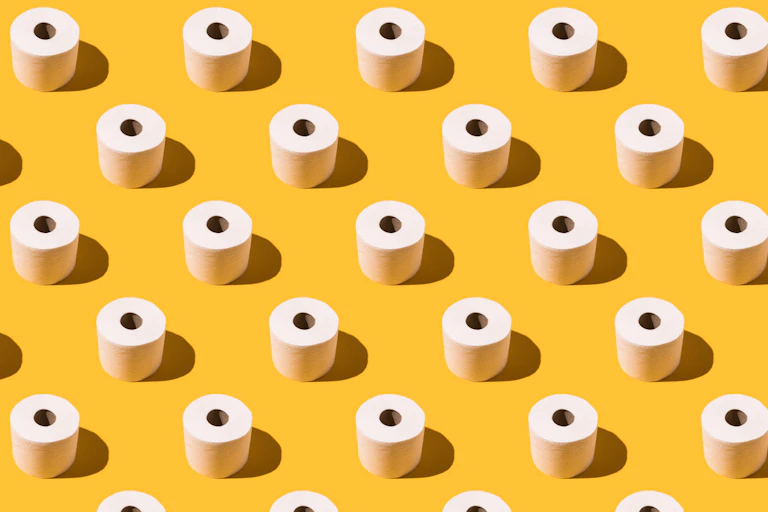 Rolls of toilet paper arranged in diagonal rows on yellow background