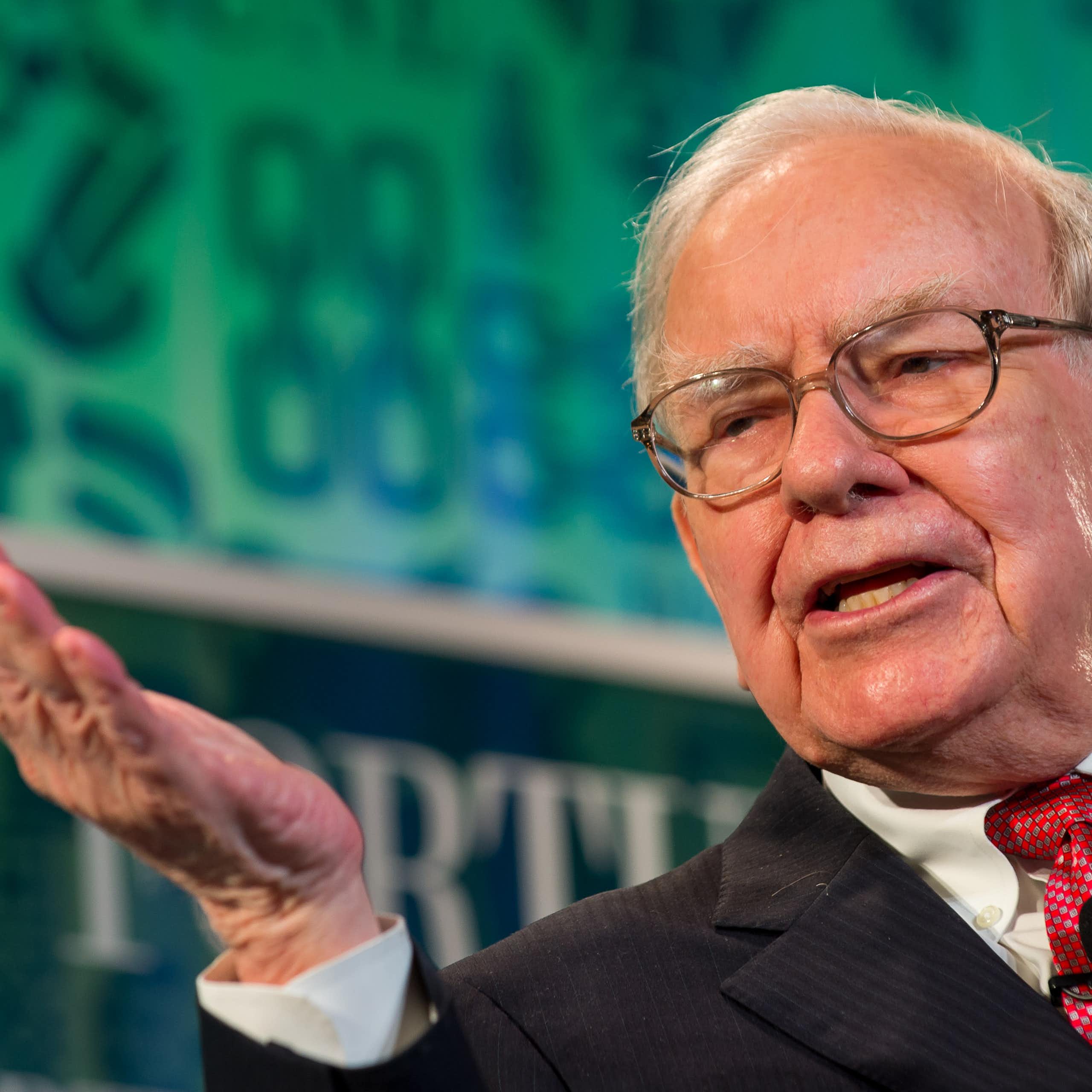 Warren Buffett wearing in a suit and tie, talking on stage.