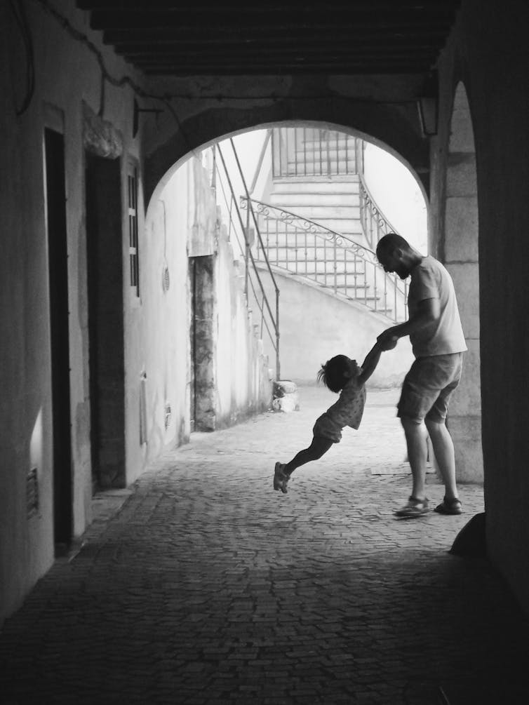 Father swinging a child in the air.