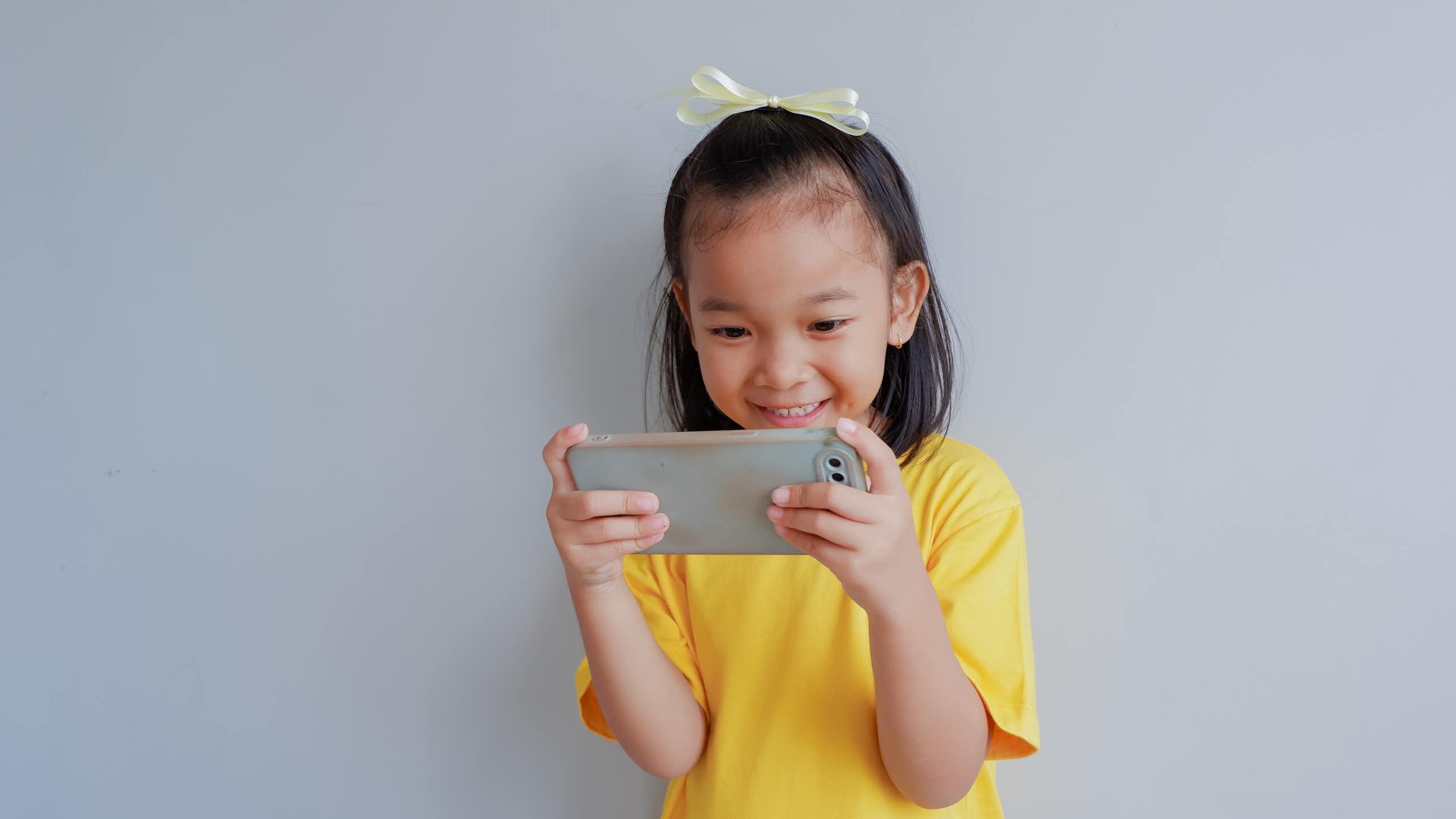 Little girl holding smart phone and smiling.