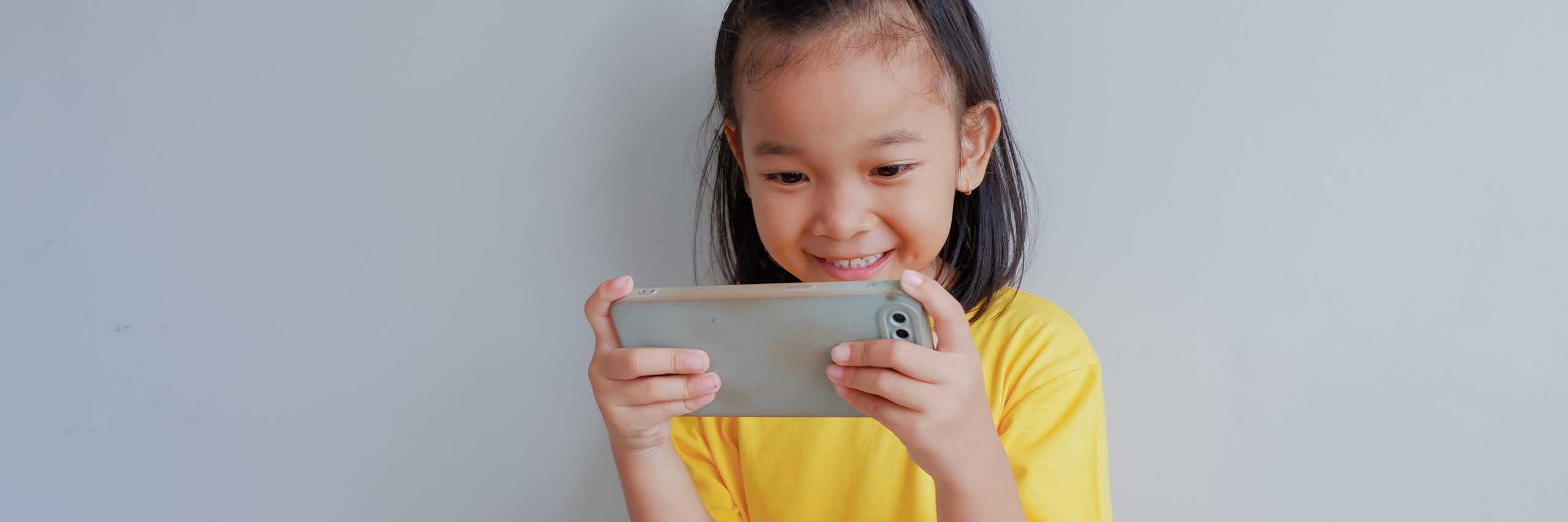 Little girl holding smart phone and smiling.