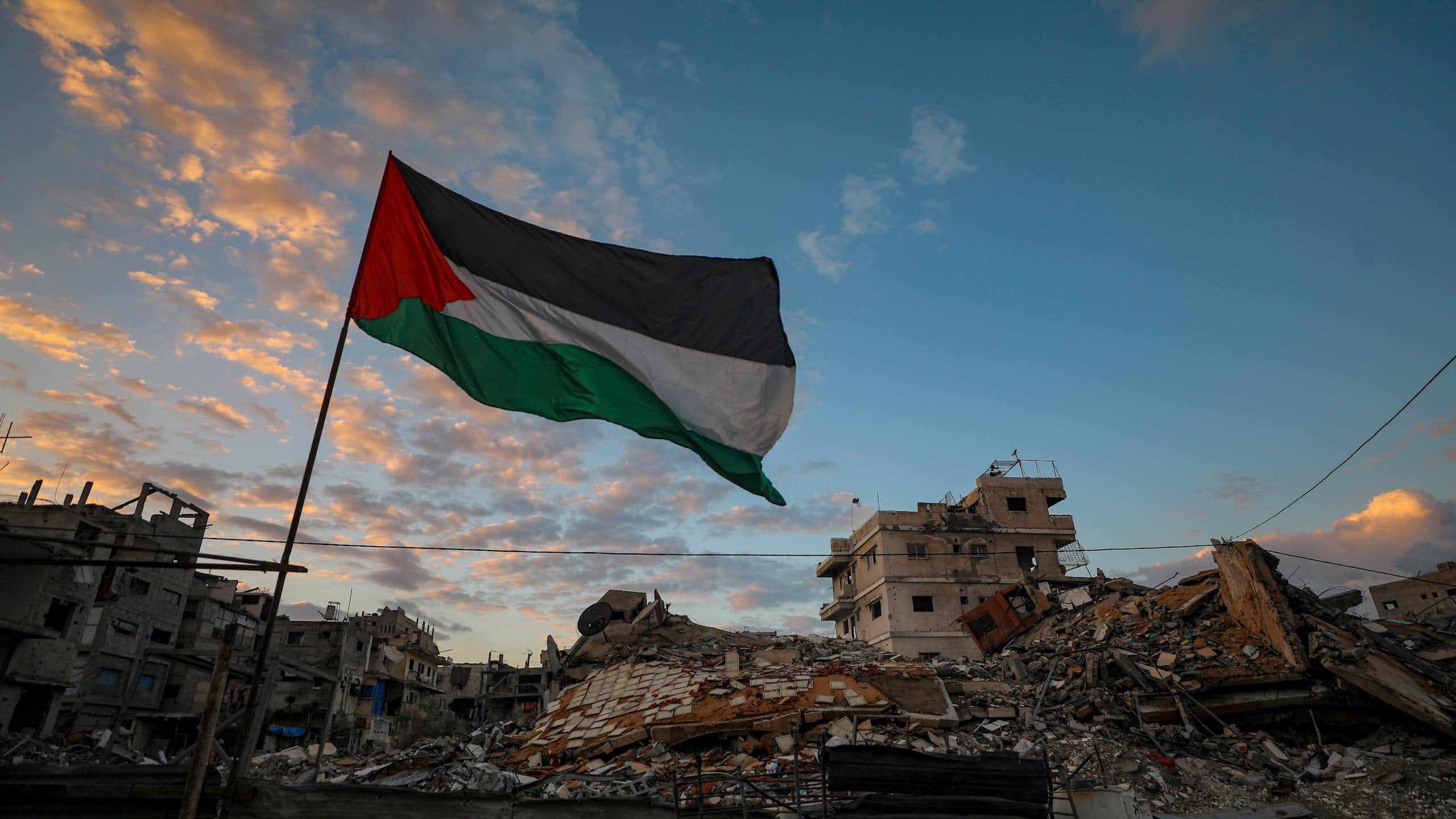 A Palestinian flag waves near the rubble of destroyed buildings in Gaza City.
