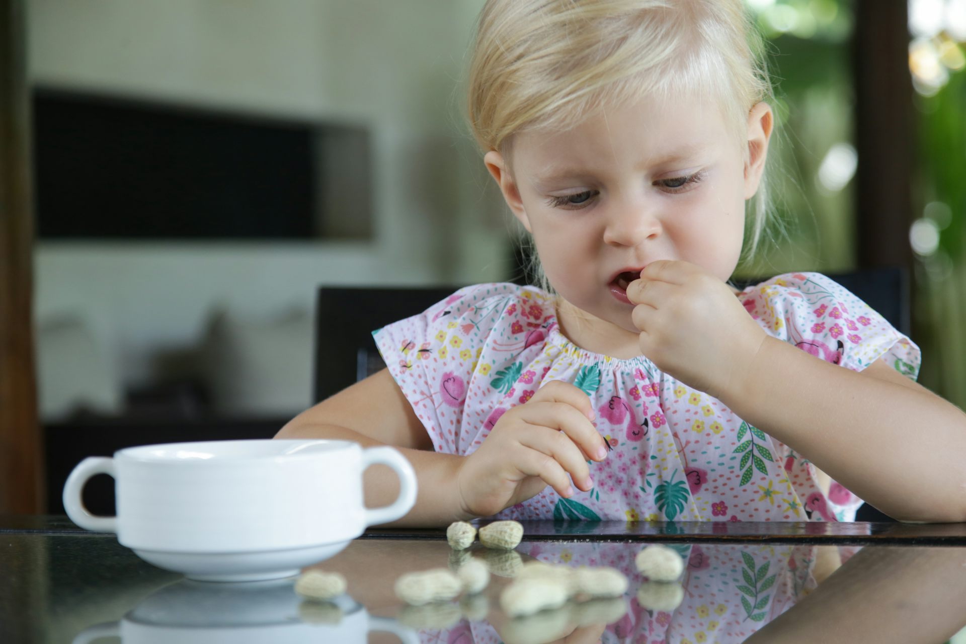 A young girl eats whole peanuts.