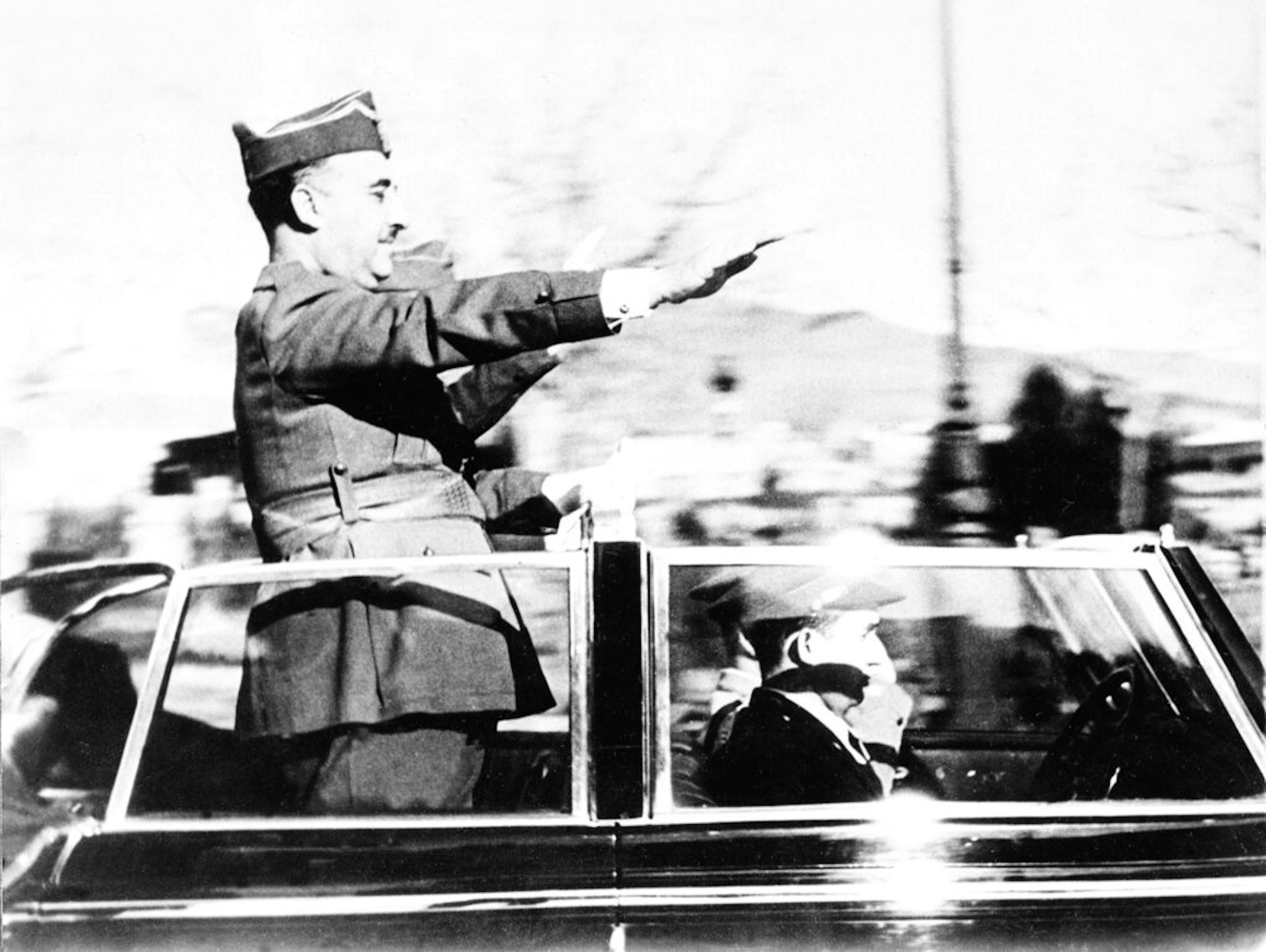 A military men salutes toward a crowd.