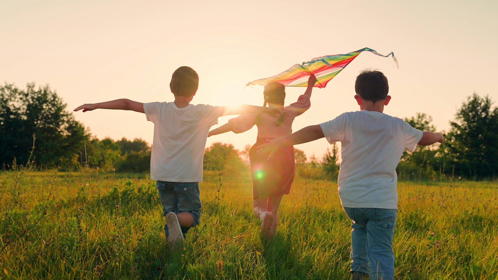 Niñosy niñas corriendo con una cometa.