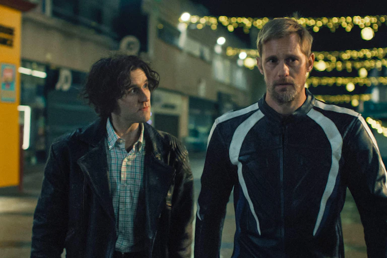 Harry Melling and Alexander Skarsgård walking down a high street in leather jackets