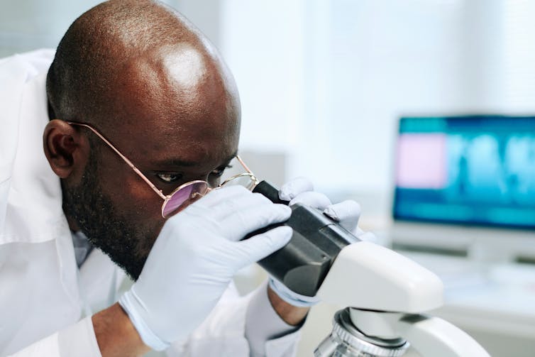 A scientist looking through a microscope in a lab.