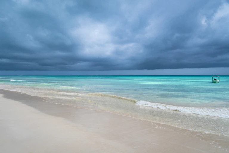 storm over tropical beach and light blue sea.