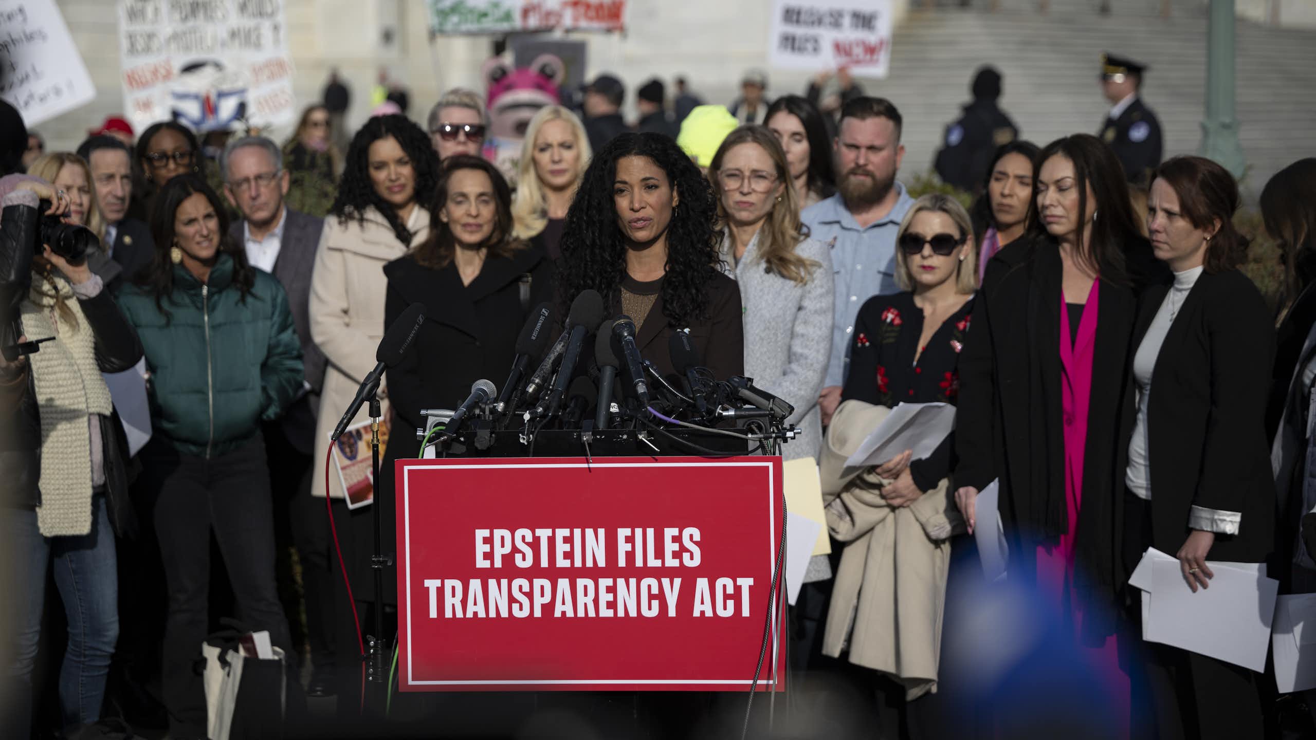 A woman speaks in front of a lectern outdoors.