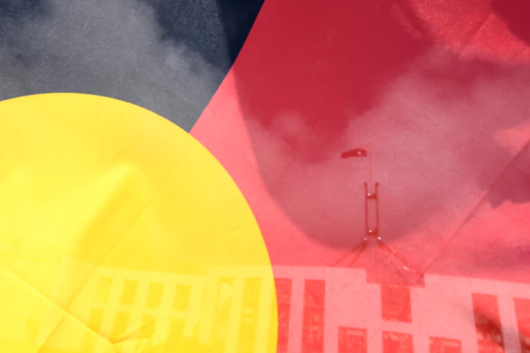 Looking through an Aboriginal flag to Parliament House in Canberra in the background.