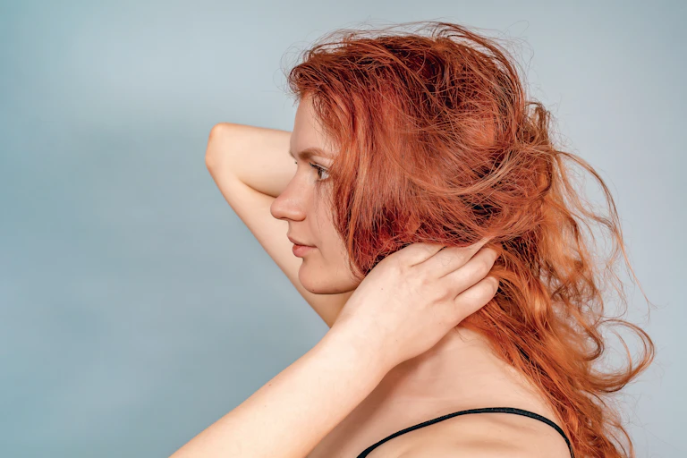 A side-profile picture of a woman with fair skin and red hair.