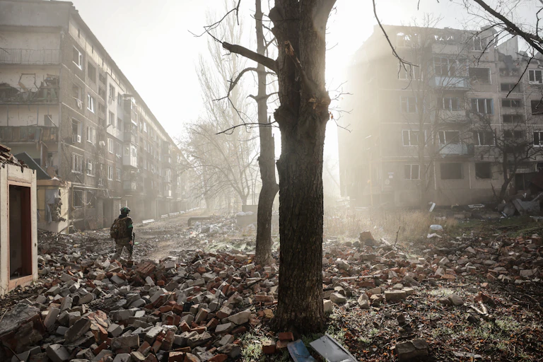 Ukrainian servicemen walk along a road in a badly damaged frontline city.