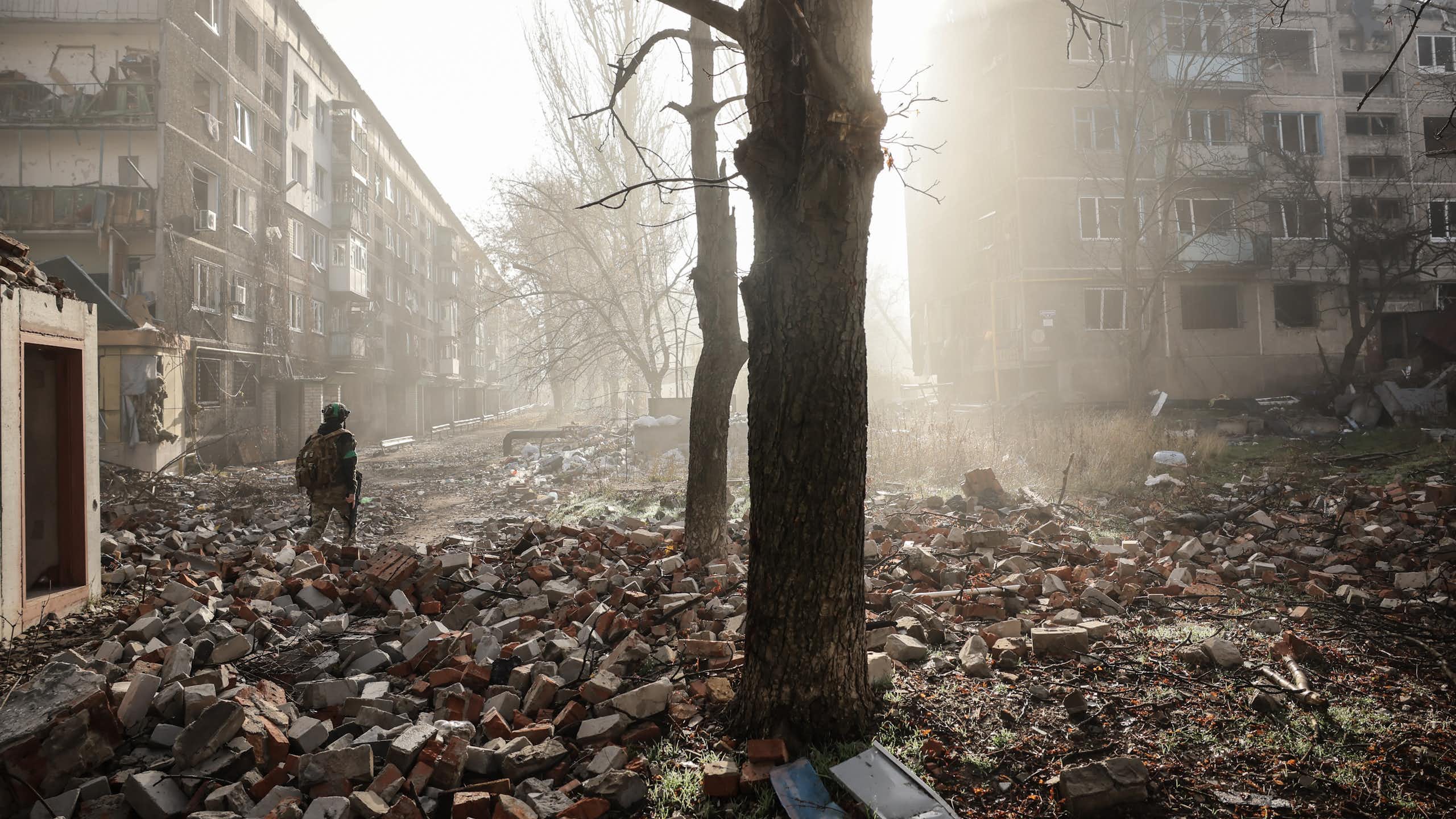 Ukrainian servicemen walk along a road in a badly damaged frontline city.