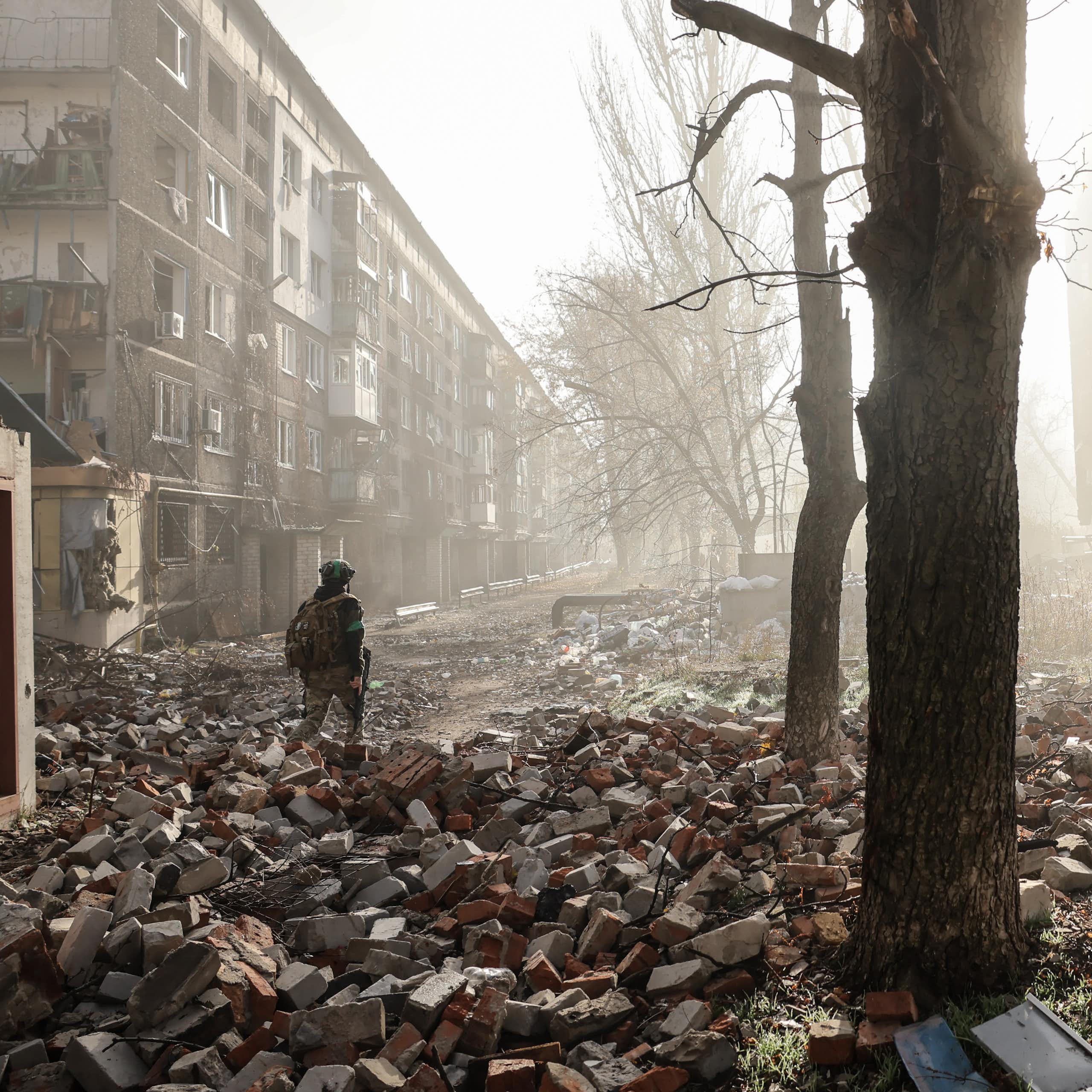 Ukrainian servicemen walk along a road in a badly damaged frontline city.