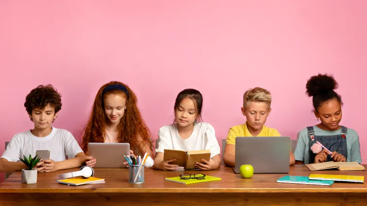 Enfants en train de lire des livres ou de consulter leurs ordinateurs