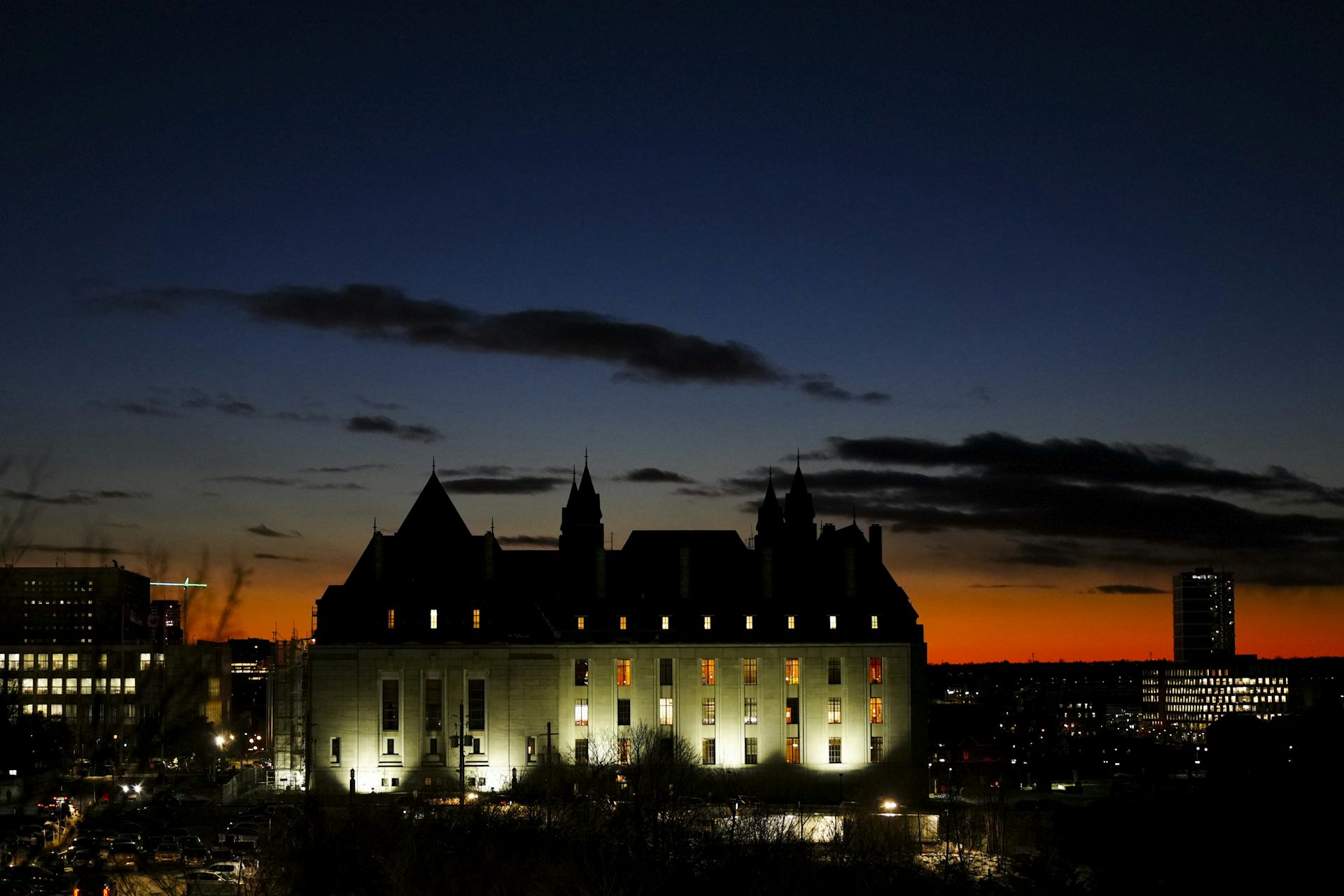 A stone building lit up against a sunset in the dusk.