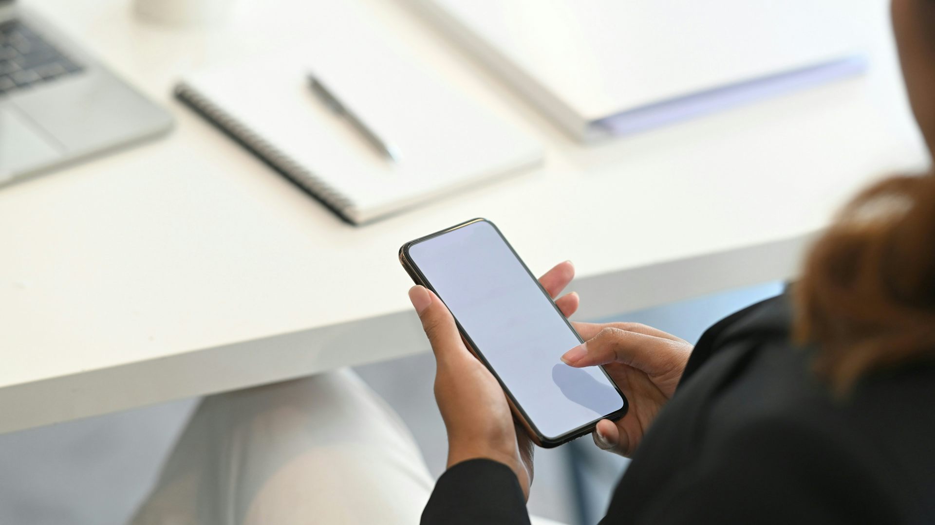 A photo of a woman from behind looking at her phone.