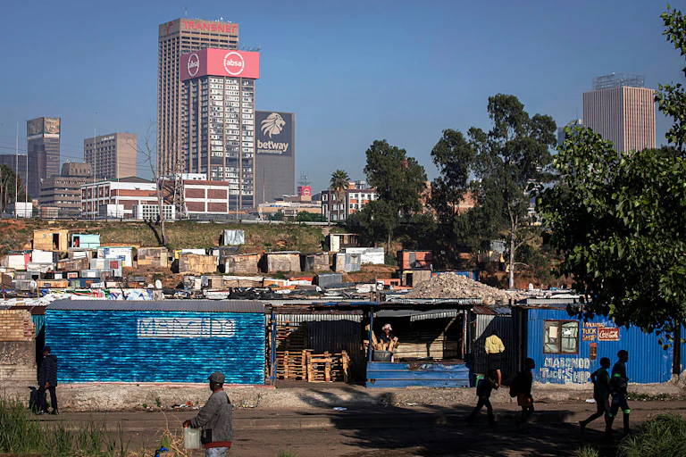 Informal settlement seen against the skyline of highrise commercial buildings.