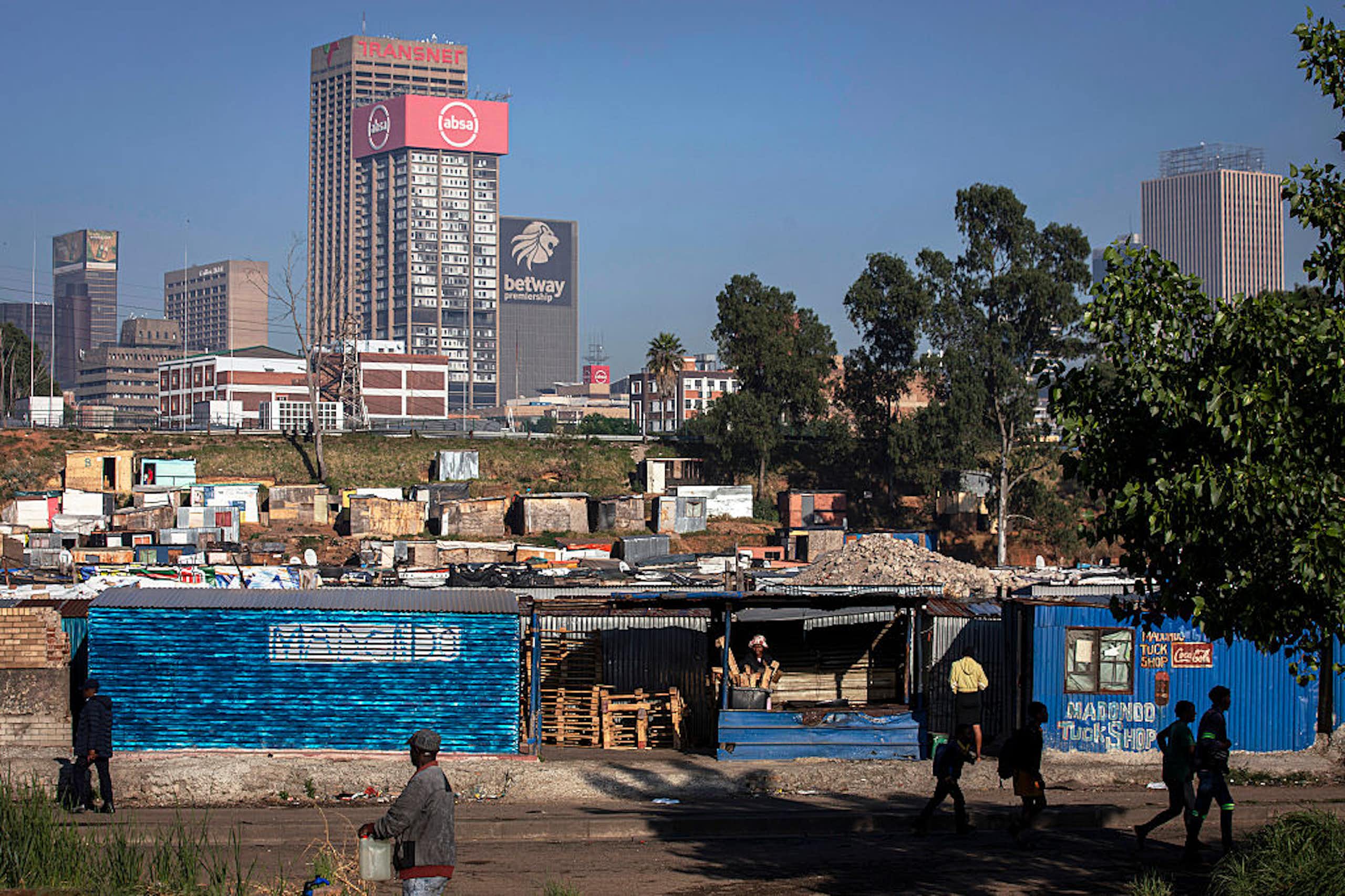 Informal settlement seen against the skyline of highrise commercial buildings.