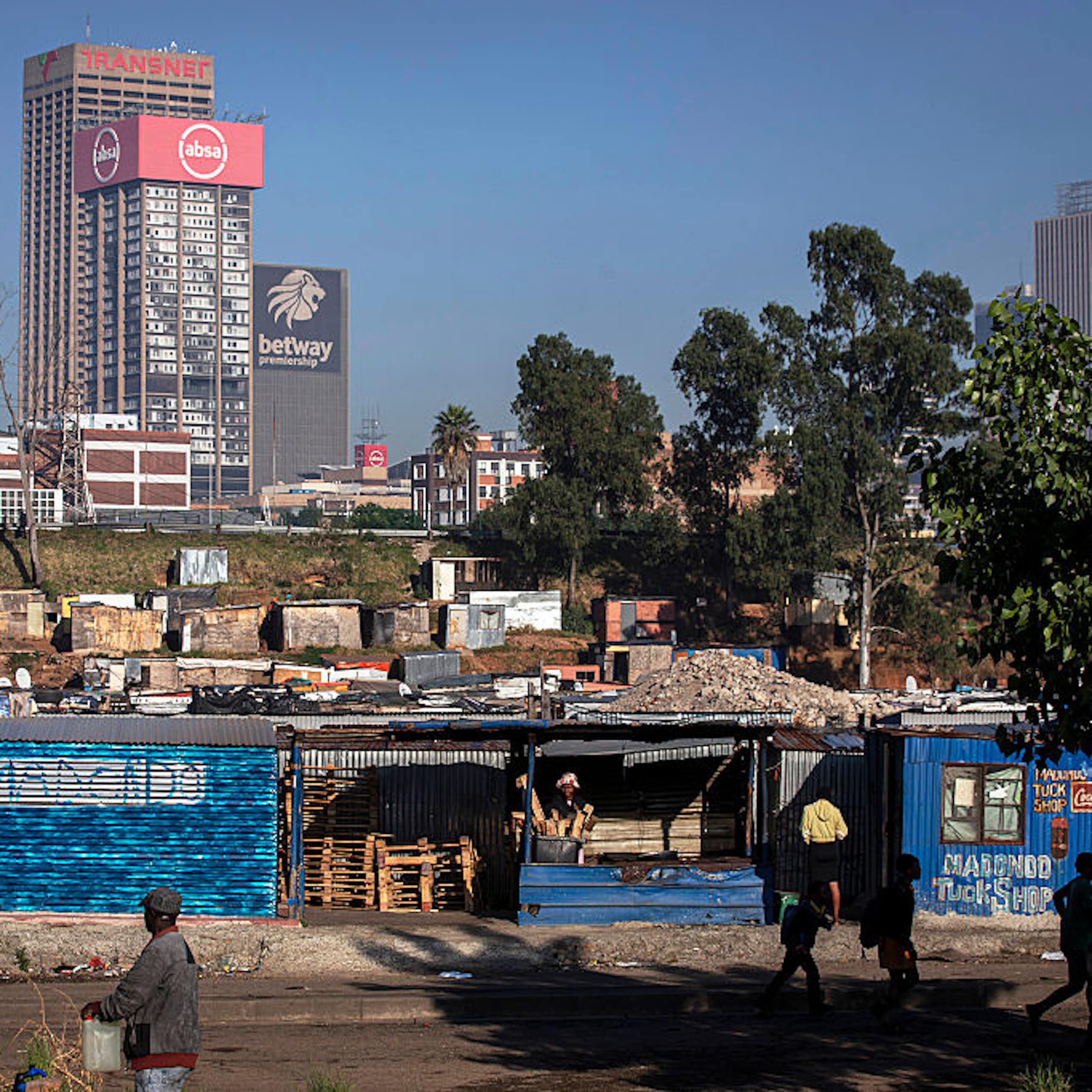 Informal settlement seen against the skyline of highrise commercial buildings.