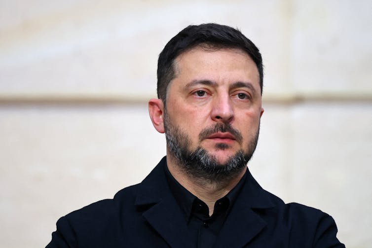 Volodymyr Zelensky looks ahead plain faced.