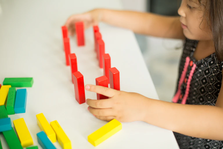 Una niña juega con bloques de madera de colores