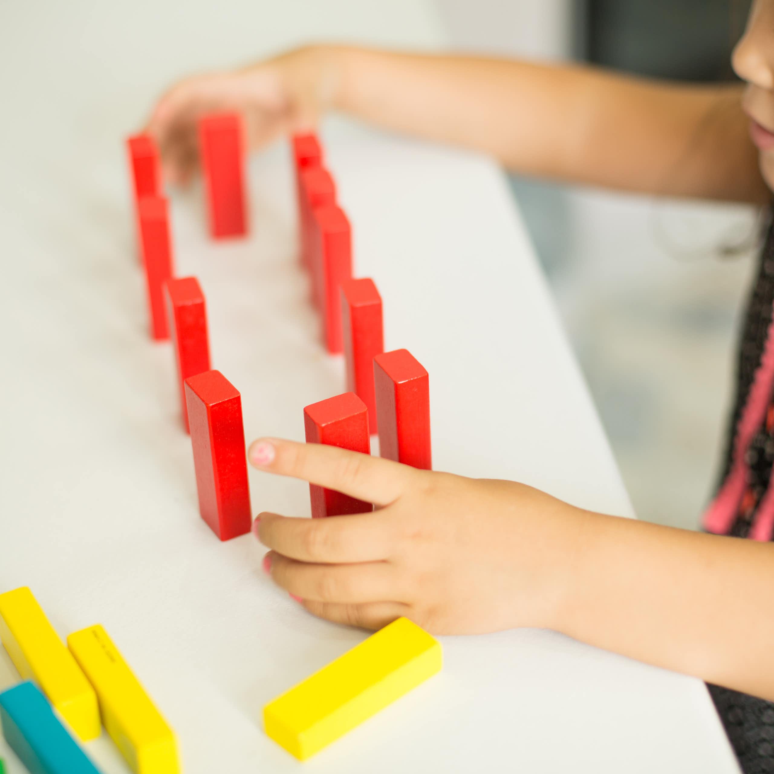 Una niña juega con bloques de madera de colores