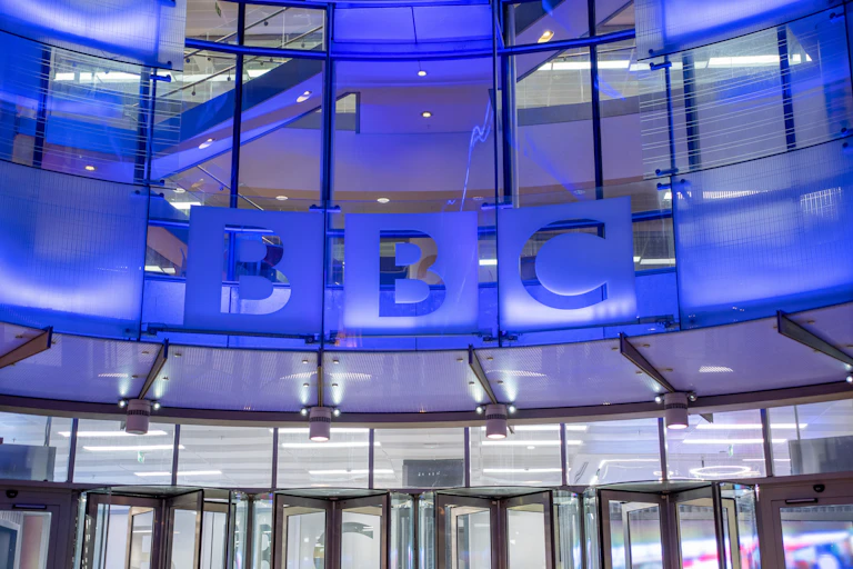 The outside of the BBC'a Broadcasting House in London lit up in blue light.