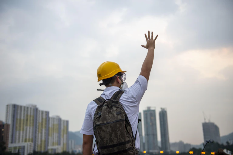 Man in yellow helmet seen from behind holds up five fingers