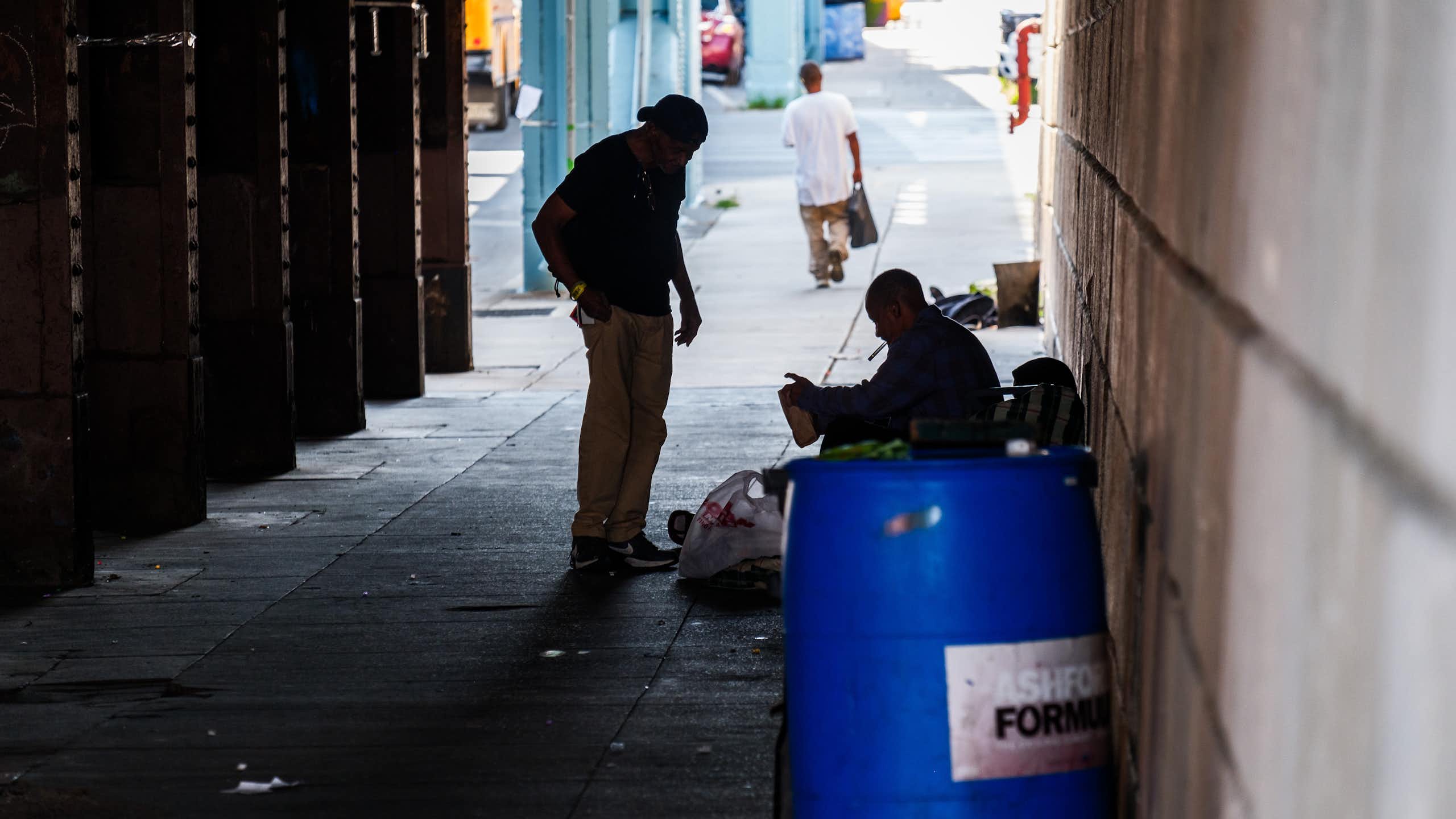 Two men in shadow speak in dimly lit area