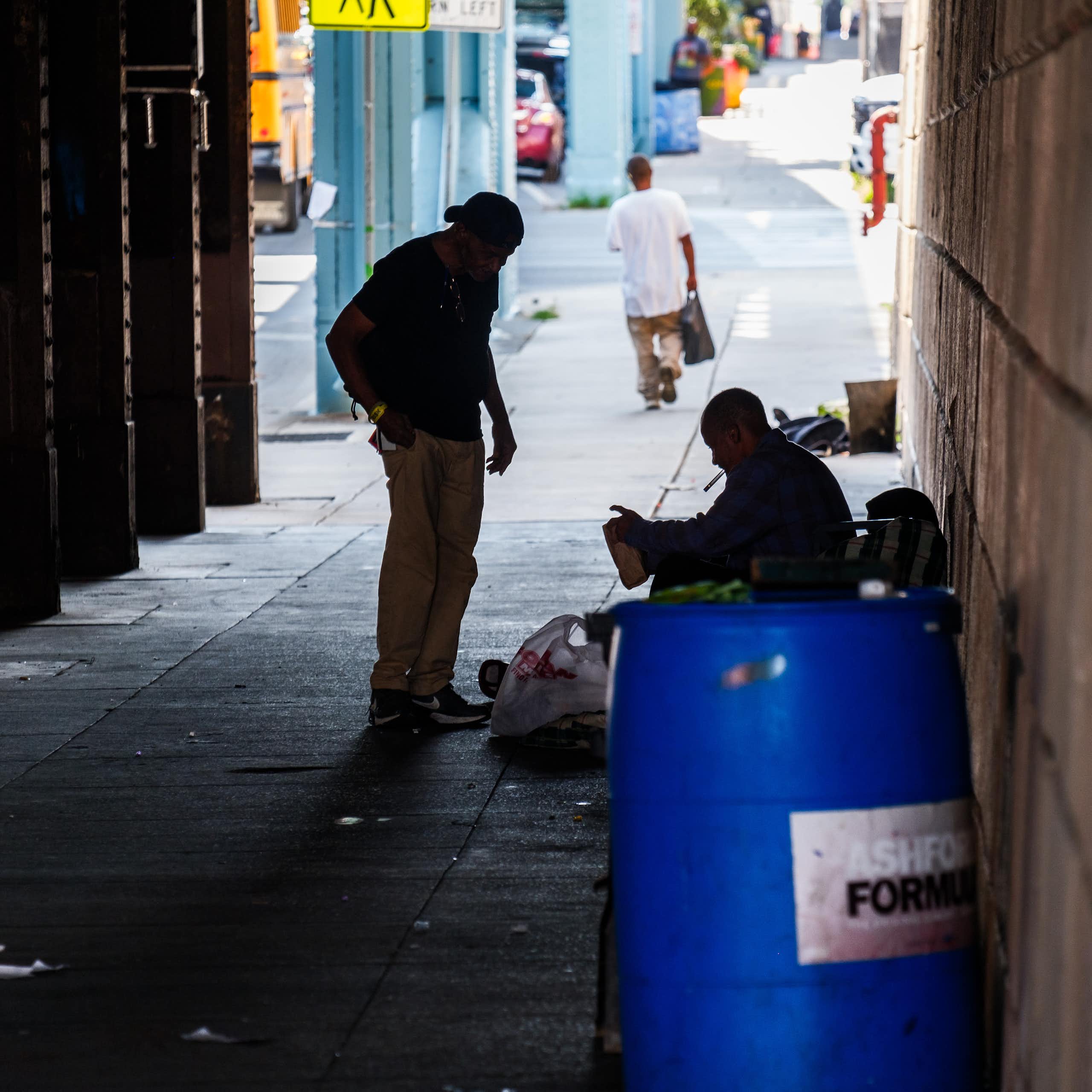 Two men in shadow speak in dimly lit area