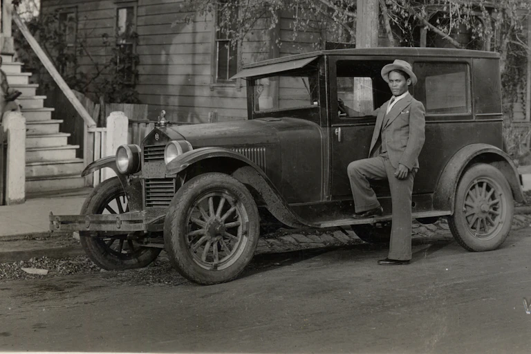A young Filipino man poses next to his car in a vintage black and white photograph.