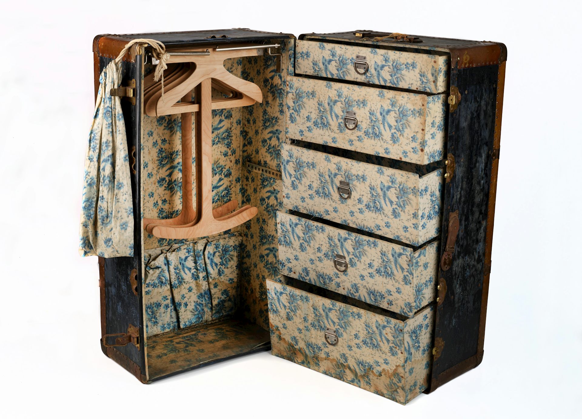 An old steamer trunk featuring clothes hangers and drawers.