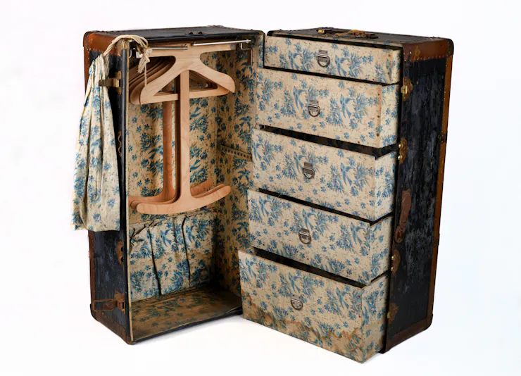 An old steamer trunk featuring clothes hangers and drawers.
