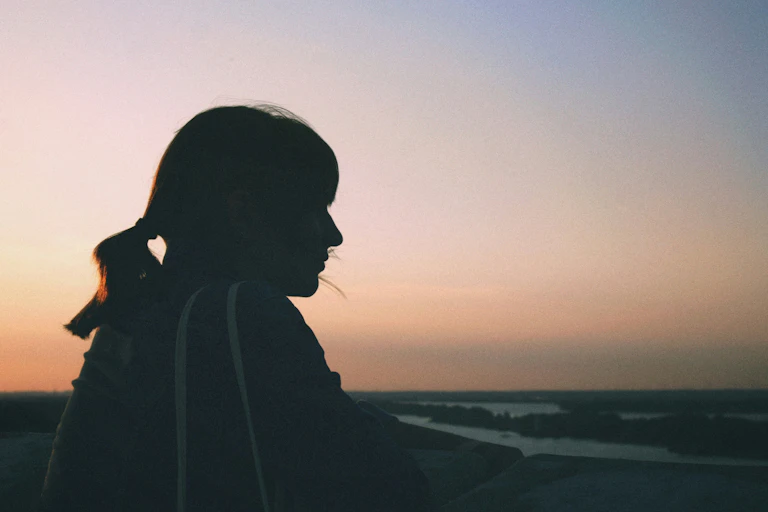 The silhouette of a young woman looking into the sunset